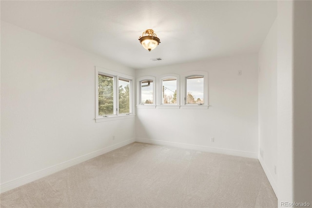 empty room with visible vents, baseboards, and light colored carpet