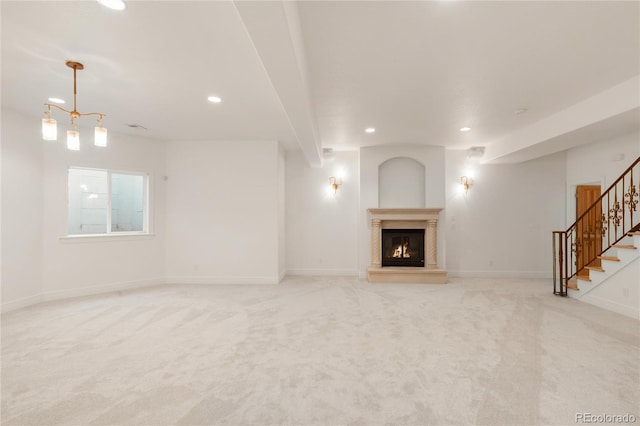 unfurnished living room featuring baseboards, stairs, light carpet, recessed lighting, and a glass covered fireplace