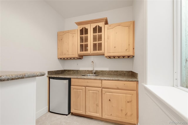 kitchen featuring light brown cabinets, freestanding refrigerator, and a sink