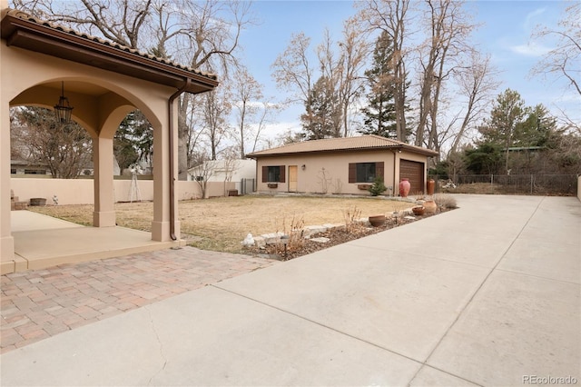 view of yard featuring decorative driveway, a patio area, an attached garage, and fence