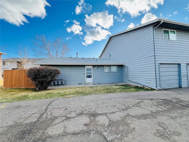 rear view of house with fence and an attached garage