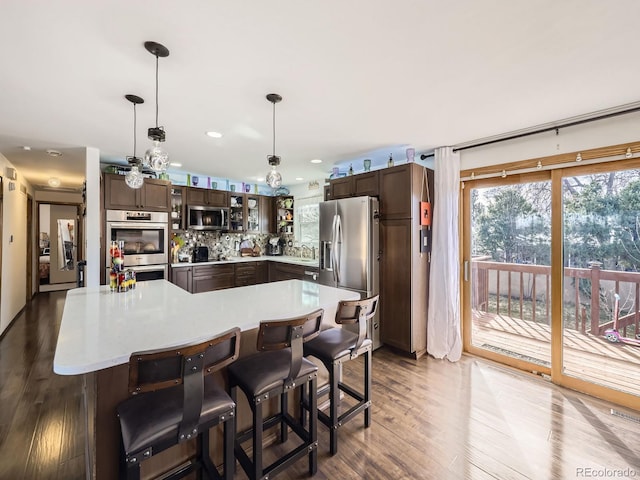 kitchen featuring appliances with stainless steel finishes, light countertops, dark brown cabinets, and pendant lighting