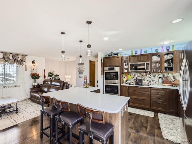 kitchen with appliances with stainless steel finishes, a center island, light countertops, and glass insert cabinets