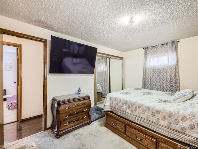 bedroom with a textured ceiling, a closet, and light carpet