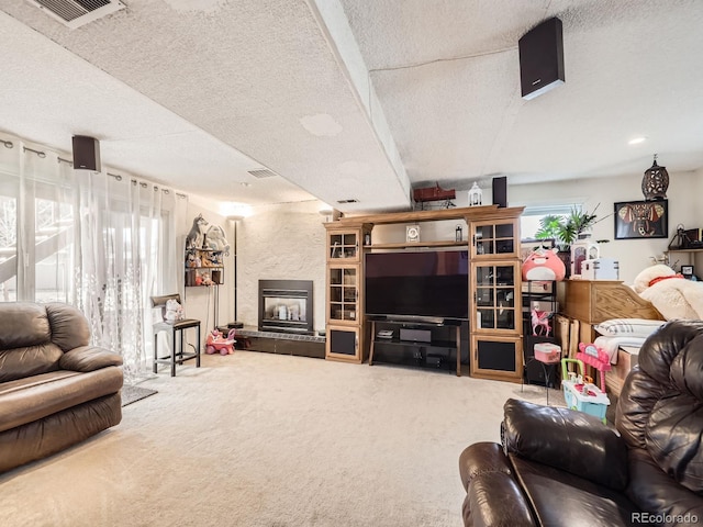 carpeted living area with a large fireplace, visible vents, and a textured ceiling