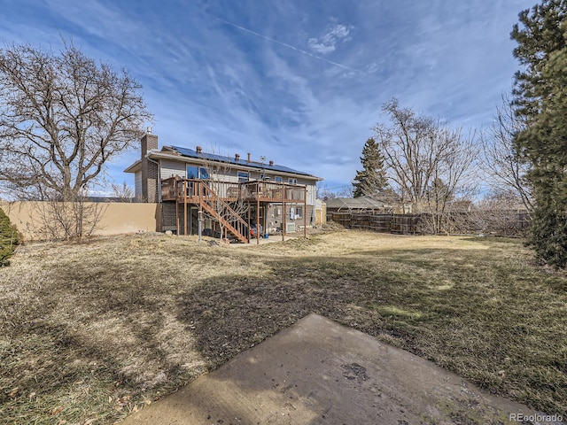 back of property featuring a deck, fence, stairway, a lawn, and a chimney