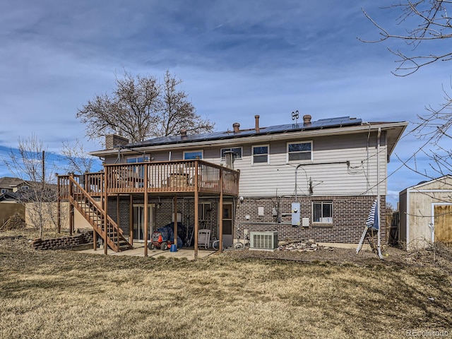 rear view of house featuring an outbuilding, stairway, a storage shed, roof mounted solar panels, and a wooden deck