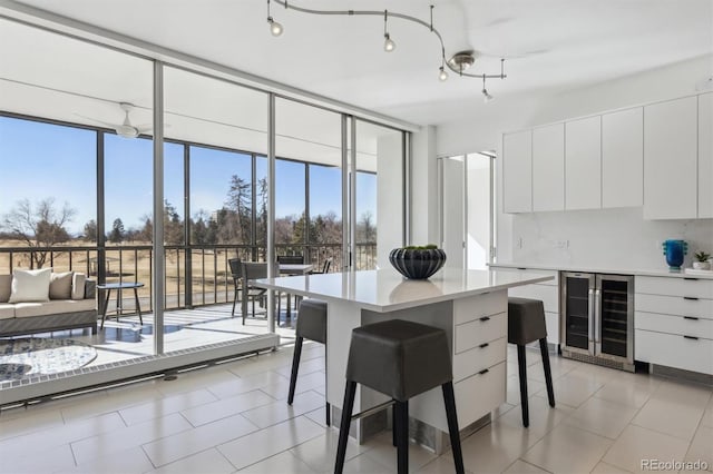 kitchen featuring beverage cooler, light countertops, expansive windows, modern cabinets, and a kitchen bar