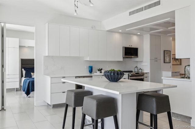 kitchen with a breakfast bar area, visible vents, decorative backsplash, appliances with stainless steel finishes, and modern cabinets