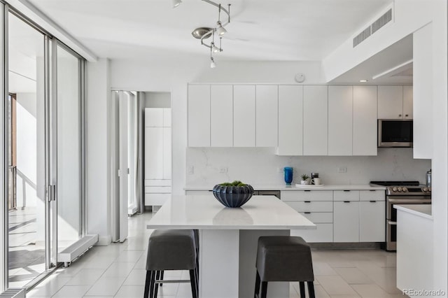 kitchen featuring a breakfast bar area, stainless steel appliances, visible vents, backsplash, and modern cabinets