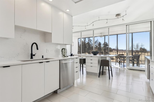 kitchen with tasteful backsplash, white cabinets, modern cabinets, stainless steel dishwasher, and a sink