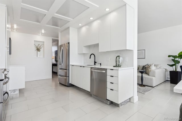 kitchen with stainless steel appliances, light countertops, a sink, and white cabinetry