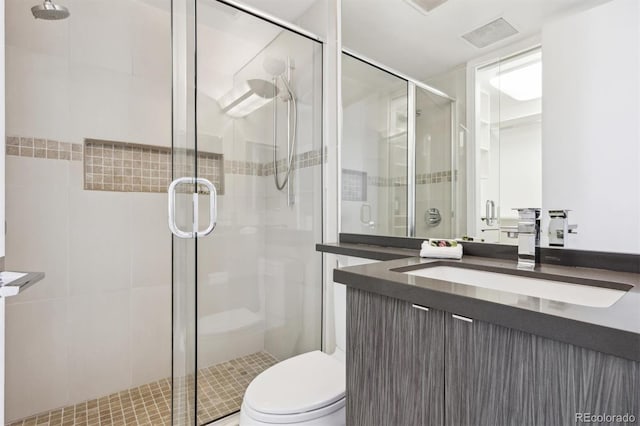 full bathroom featuring visible vents, vanity, a shower stall, and toilet