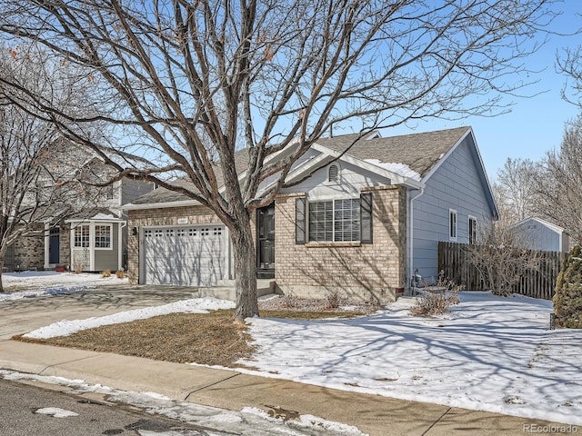 view of front of property with driveway, brick siding, an attached garage, and fence