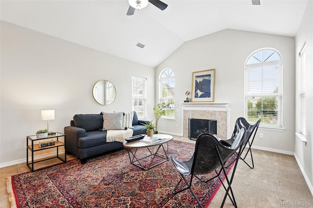 living area featuring ceiling fan, visible vents, a tile fireplace, baseboards, and lofted ceiling
