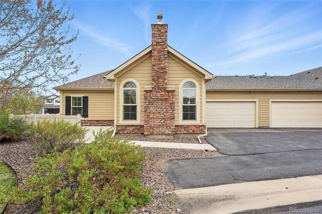 single story home with driveway, a chimney, a garage, fence, and stone siding