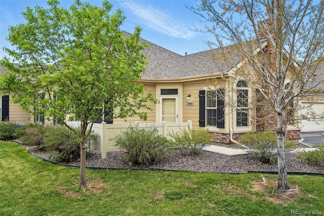 view of front facade featuring fence, a chimney, roof with shingles, and a front lawn