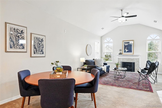carpeted dining room with visible vents, baseboards, a ceiling fan, vaulted ceiling, and a premium fireplace