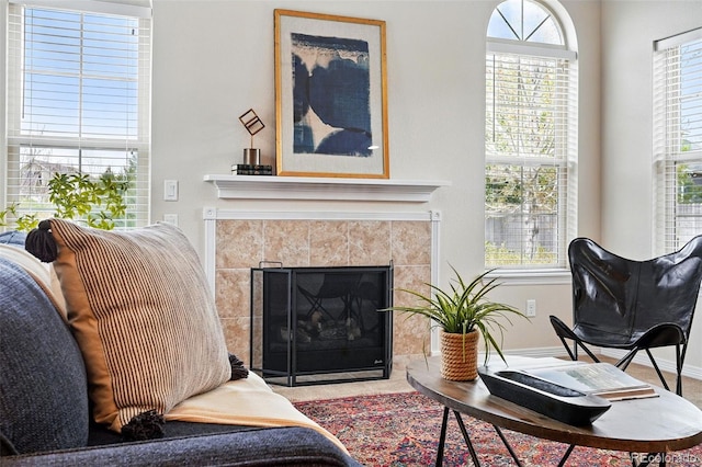 living area with baseboards and a tile fireplace