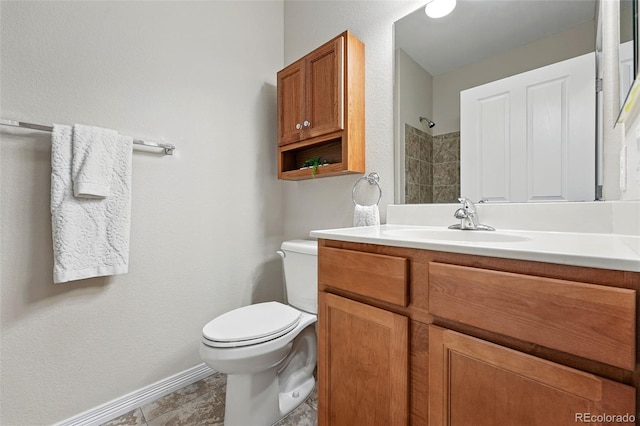 bathroom with toilet, baseboards, a shower, and vanity