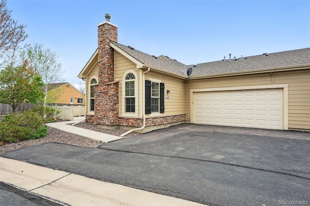 view of front facade featuring a garage, fence, stone siding, a chimney, and driveway
