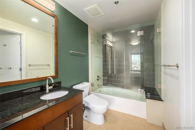 full bathroom featuring tile patterned flooring, bath / shower combo with glass door, vanity, and toilet