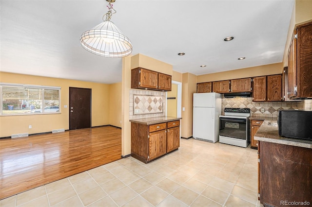 kitchen with range hood, visible vents, freestanding refrigerator, electric stove, and tasteful backsplash