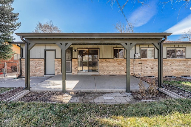 exterior space with brick siding, board and batten siding, and fence