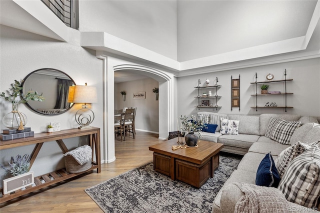 19935 E Stanford Dr, Centennial, CO 80015 - living room featuring arched walkways, a high ceiling, light wood-style flooring, and baseboards