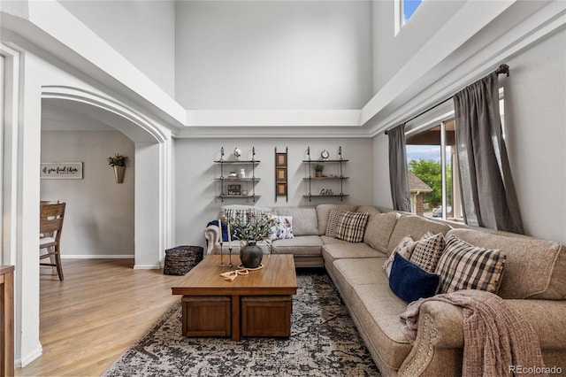 19935 E Stanford Dr, Centennial, CO 80015 - living room featuring a high ceiling, light wood-type flooring, arched walkways, and baseboards