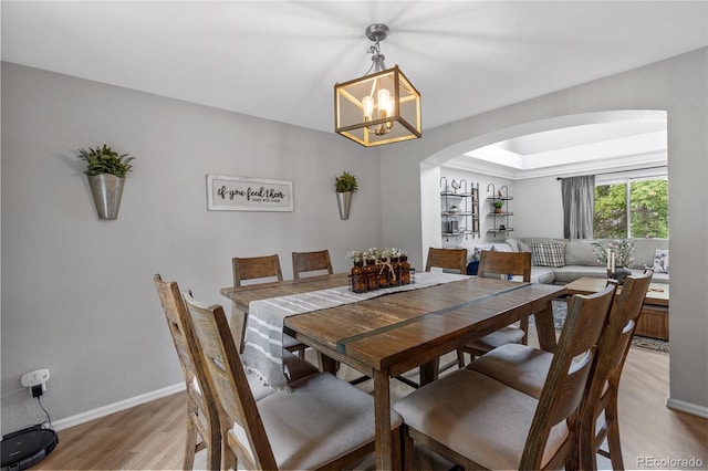 19935 E Stanford Dr, Centennial, CO 80015 - dining space featuring arched walkways, light wood-style flooring, a chandelier, and baseboards