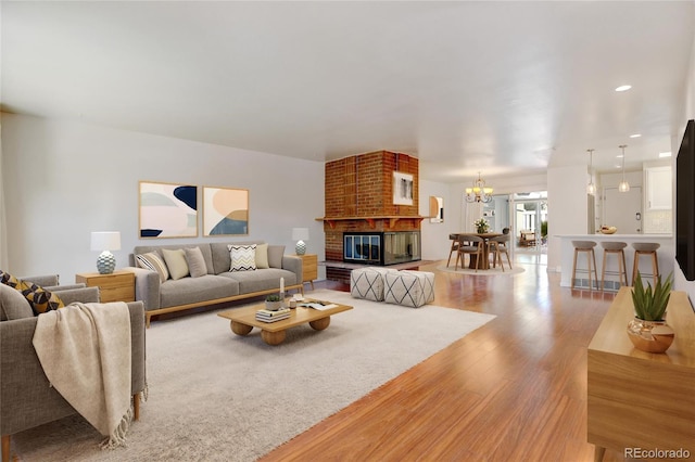 living room with wood-type flooring, a chandelier, and a fireplace