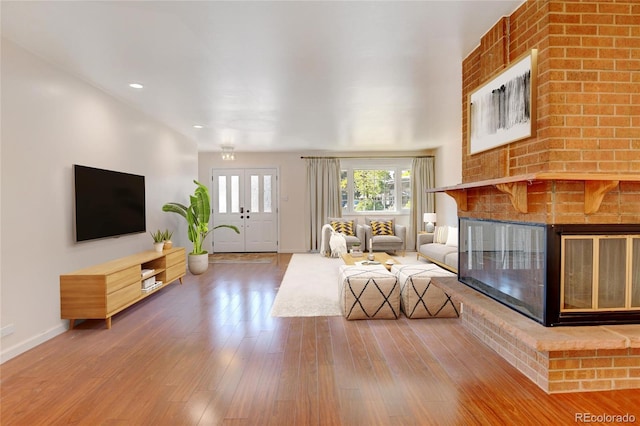 living room featuring wood-type flooring and a brick fireplace