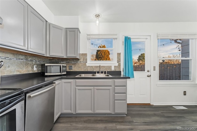 kitchen featuring dark hardwood / wood-style flooring, backsplash, gray cabinetry, stainless steel appliances, and sink