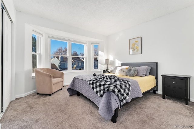 bedroom featuring a textured ceiling, light colored carpet, and a closet