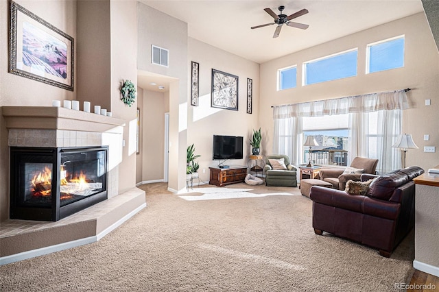 living room featuring carpet flooring, a tile fireplace, and ceiling fan