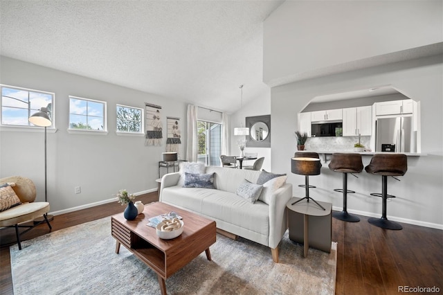 4882 W 68th Ave Unit 4, Westminster, CO 80030 - living room with dark wood finished floors, baseboards, vaulted ceiling, and arched walkways