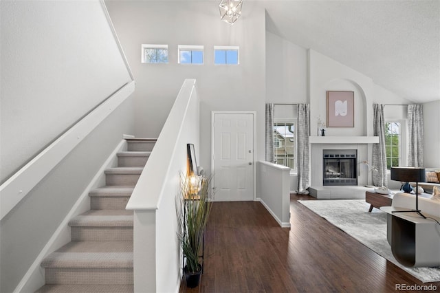 4882 W 68th Ave Unit 4, Westminster, CO 80030 - stairway featuring wood finished floors, high vaulted ceiling, baseboards, and a fireplace with raised hearth