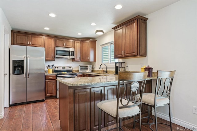 4750 S Dudley St Unit 21, Littleton, CO 80123 - kitchen featuring stainless steel appliances, a peninsula, light stone countertops, dark wood-style flooring, and recessed lighting