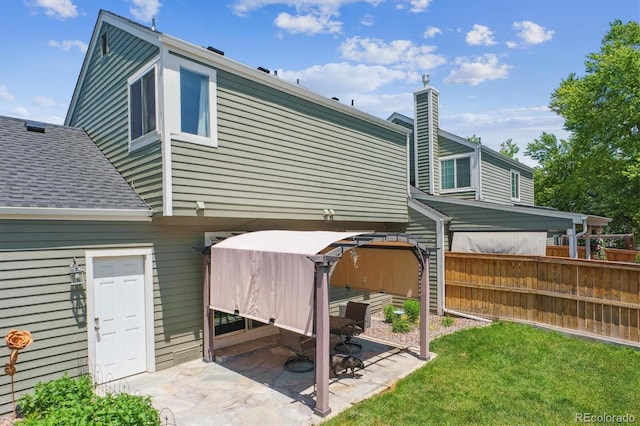 4750 S Dudley St Unit 21, Littleton, CO 80123 - rear view of house featuring a patio, a shingled roof, a chimney, and a hot tub