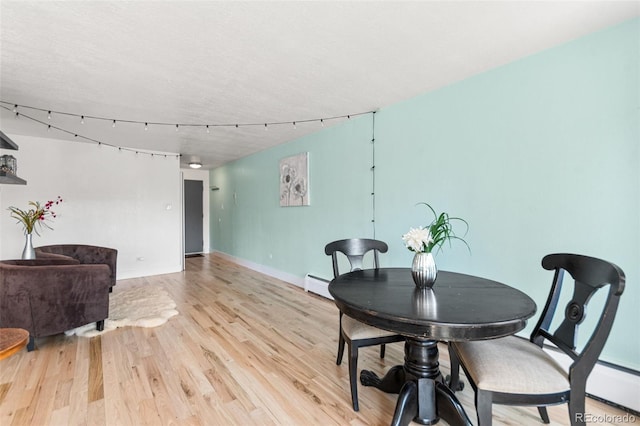 75 N Emerson St Unit 206, Denver, CO 80218 - dining room with light wood-type flooring, baseboard heating, baseboards, and a textured ceiling