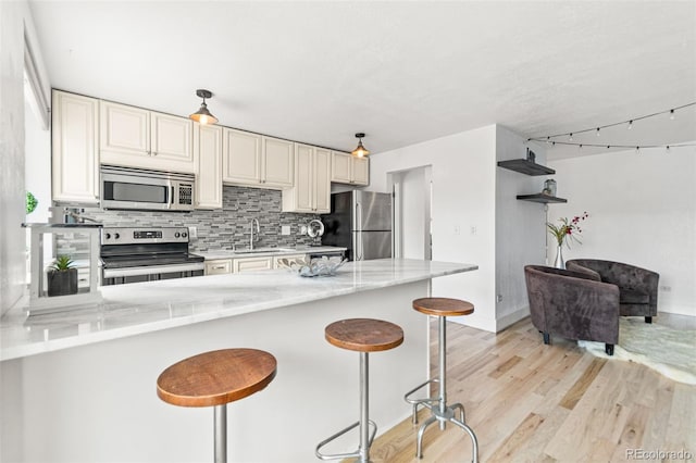 75 N Emerson St Unit 206, Denver, CO 80218 - kitchen with appliances with stainless steel finishes, a sink, backsplash, a peninsula, and light wood-style flooring