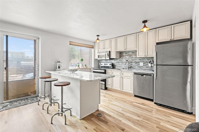 75 N Emerson St Unit 206, Denver, CO 80218 - kitchen with stainless steel appliances, light wood finished floors, decorative backsplash, a sink, and a peninsula