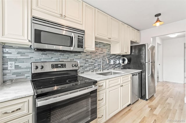 75 N Emerson St Unit 206, Denver, CO 80218 - kitchen featuring appliances with stainless steel finishes, a sink, cream cabinets, tasteful backsplash, and light wood finished floors