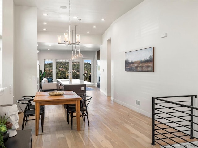 dining space with sink, a notable chandelier, and light hardwood / wood-style flooring