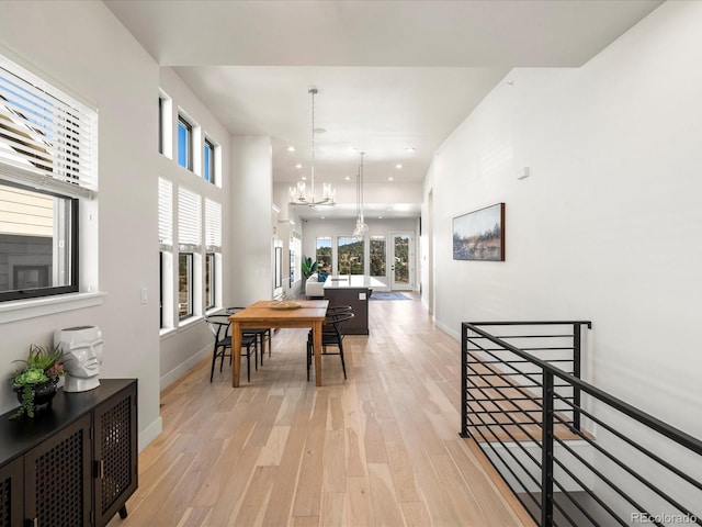 hallway with light wood-type flooring and an inviting chandelier