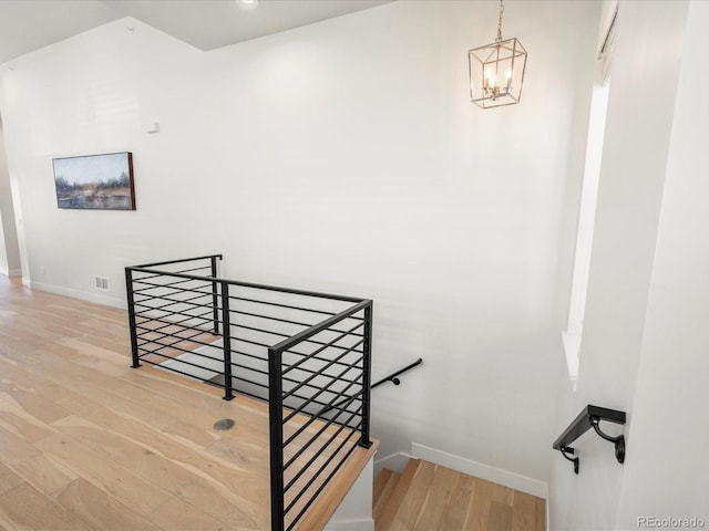 stairway featuring wood-type flooring and a notable chandelier