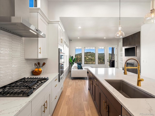 kitchen featuring white cabinetry, appliances with stainless steel finishes, sink, and wall chimney range hood