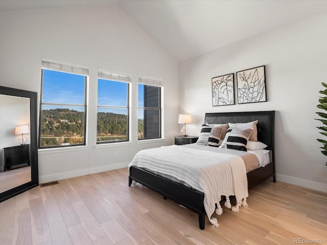 bedroom featuring light hardwood / wood-style flooring and high vaulted ceiling