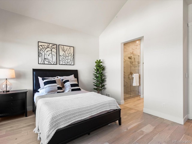 bedroom with ensuite bathroom, high vaulted ceiling, and light hardwood / wood-style floors